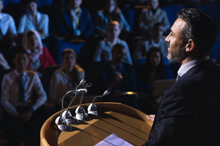 High angle view of Caucasian businessman public speaking standing and giving presentation in the auditorium